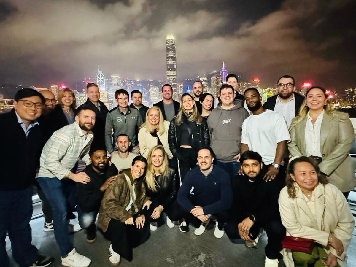Time Doctor global sales team at the Hong Kong sales kickoff 2025, Victoria Harbour skyline behind